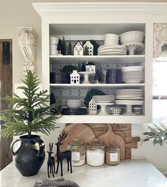 a kitchen counter with dishes and utensils on it, next to a potted plant