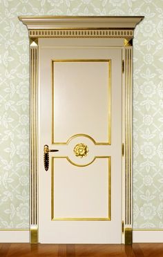 a white door with gold trim in front of a green wallpapered wall and wooden floor