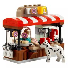 a lego dog stands in front of a small food stand with donuts and doughnuts