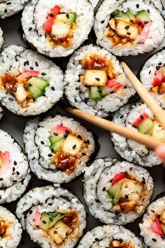 sushi rolls with chopsticks on top of them and various toppings in the middle