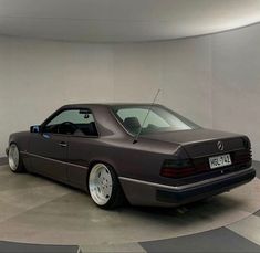 a gray car parked in a garage next to a white wall and round flooring