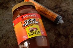 a jar of cajun injector next to an orange tube