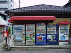 vending machines are lined up on the side of the street in front of a building