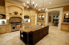 a large kitchen with an island and chandelier in the center, surrounded by beige cabinets