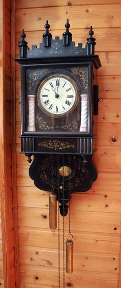 an old clock hanging from the side of a wooden wall