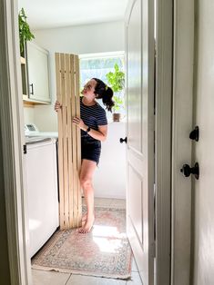 a woman standing in front of a door with a wooden slat on the floor