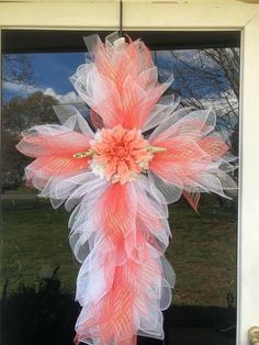 a pink and white wreath hanging on the front door