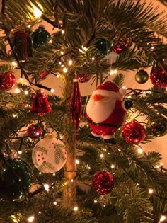 a christmas tree with ornaments on it and santa clause ornament hanging from the top