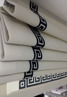 white sheets with black greek designs on them in a store window sill, ready to be folded