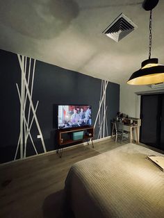 a bedroom with a bed, television and desk in it's corner area at night