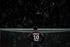 a soccer player standing in front of a net with his back turned to the camera