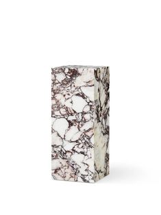 a white and brown marble vase sitting on top of a table next to a wall