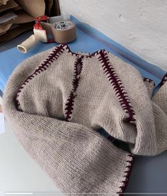 a knitted blanket sitting on top of a table next to some rolls of tape