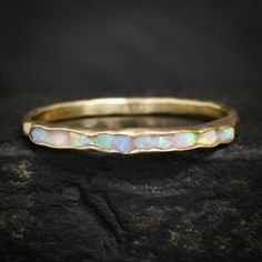 a gold band with white opal inlays on top of a black rock