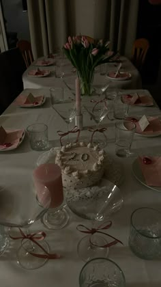 a table set for a birthday party with a cake and flowers in vases on it