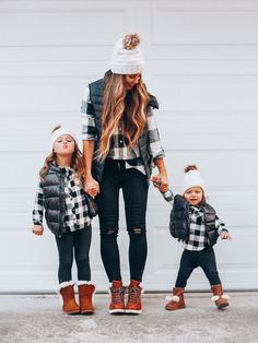 a mother and her two children wearing winter clothes, one is holding the hand of another child