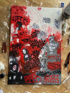 a painting with red and black graffiti on it sitting on top of a wooden floor