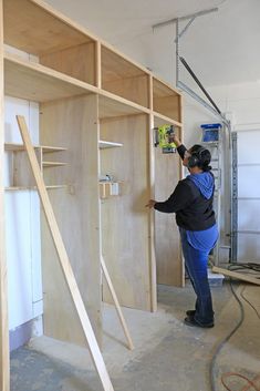 a woman is working on some shelves in a room