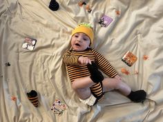 a baby laying on top of a bed wearing a yellow and black striped shirt with matching socks