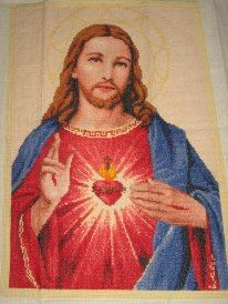 a cross stitched picture of jesus holding a heart