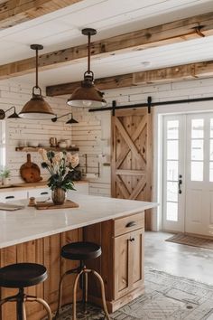 a kitchen island with two stools in front of it and an open door leading to the outside