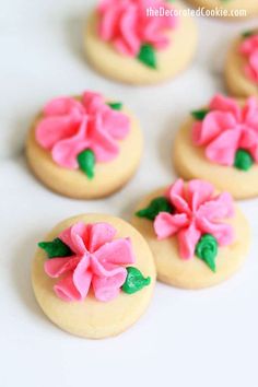 decorated cookies with pink icing and green leaves on top are arranged in a circle