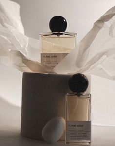 two perfume bottles sitting next to each other on top of a white sheeted surface