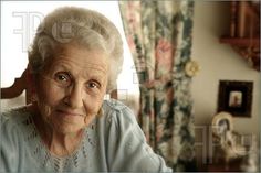 an old woman looking at the camera with her eyes wide open in front of a window