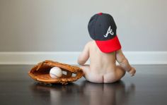 a baby sitting on the floor with a baseball mitt