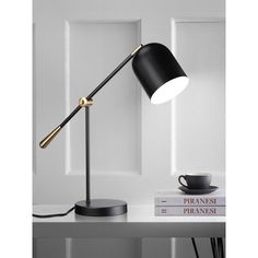 a black and gold desk lamp on top of a white table next to a stack of books