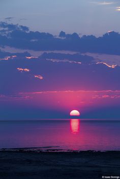 the sun is setting over the ocean with clouds in the sky and water below it