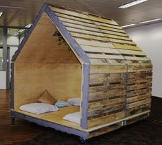 a bed made out of pallet wood in the shape of a house with pillows on it