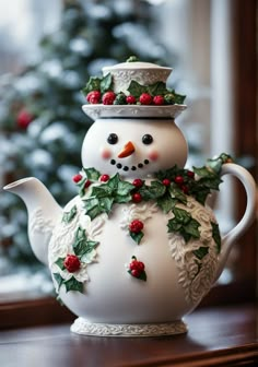 a snowman teapot with holly and berries on it