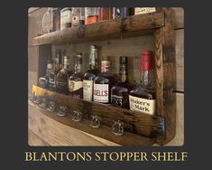 a wooden shelf filled with bottles and glasses on top of a wall next to a sign that says blanton's stopper shelf