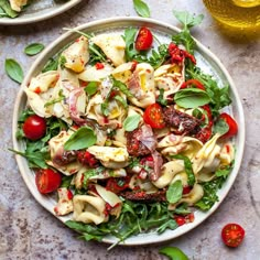 two plates of pasta salad with tomatoes, spinach and other ingredients on the table