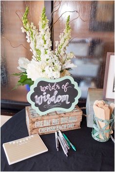 a table topped with a wooden sign and flowers