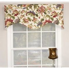 a window with a flowered valance hanging from it's side next to a lamp