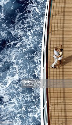 two people are standing on the deck of a boat in the middle of the ocean