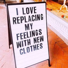 a sign that says i love replacing my feelings with new clothes on the sidewalk