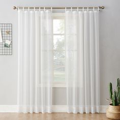 a white curtain hanging on a wall next to a potted cactus in front of a window