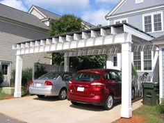 two cars are parked in front of a house with a pergolan attached to it