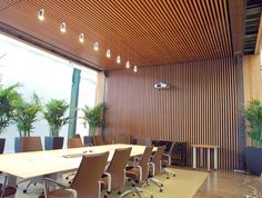 an empty conference room with wooden walls and ceiling lights, along with chairs and tables