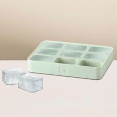 an ice tray and two plastic containers on a table