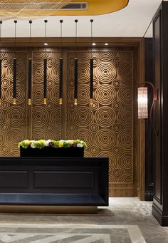 an elegant reception area with gold and black wallpaper, chandeliers and flowers