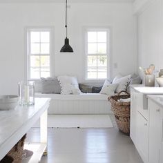 a kitchen with white walls and flooring next to two windows in the center of the room