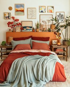 a bed with red and blue sheets in a room filled with pictures on the wall