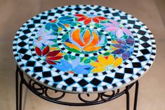 a multicolored mosaic table with metal stand on tile flooring and beige tiles