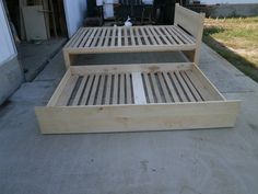 a wooden bed frame sitting on top of a cement floor next to a garage door