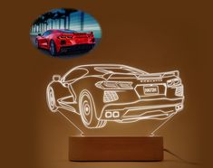 a red sports car is shown in the shape of a night light on a wooden stand