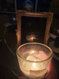 a person holding a lit candle in front of a mirror with a reflection on it